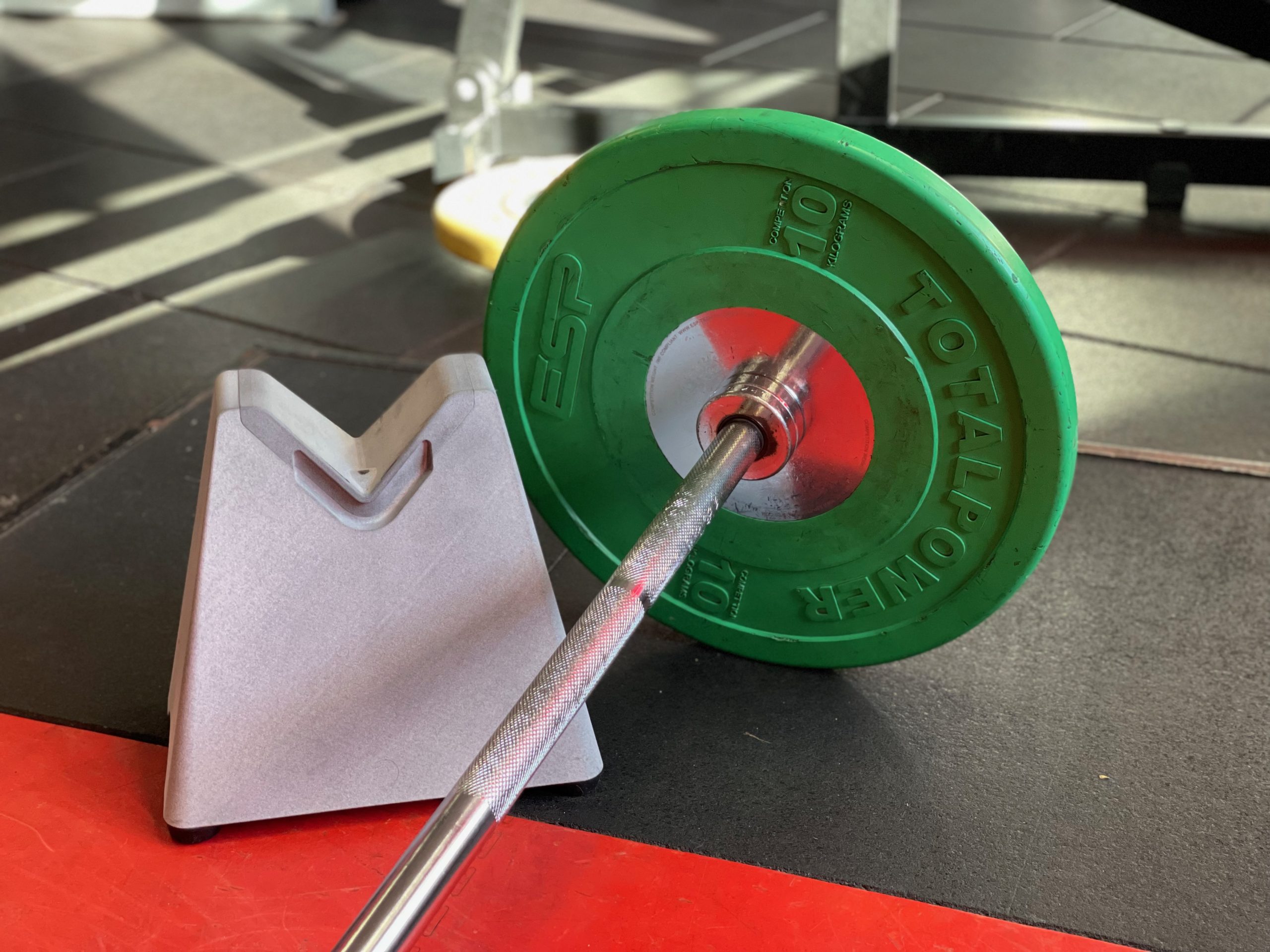 Barbell resting in the BarBuddi V, loaded with a plate